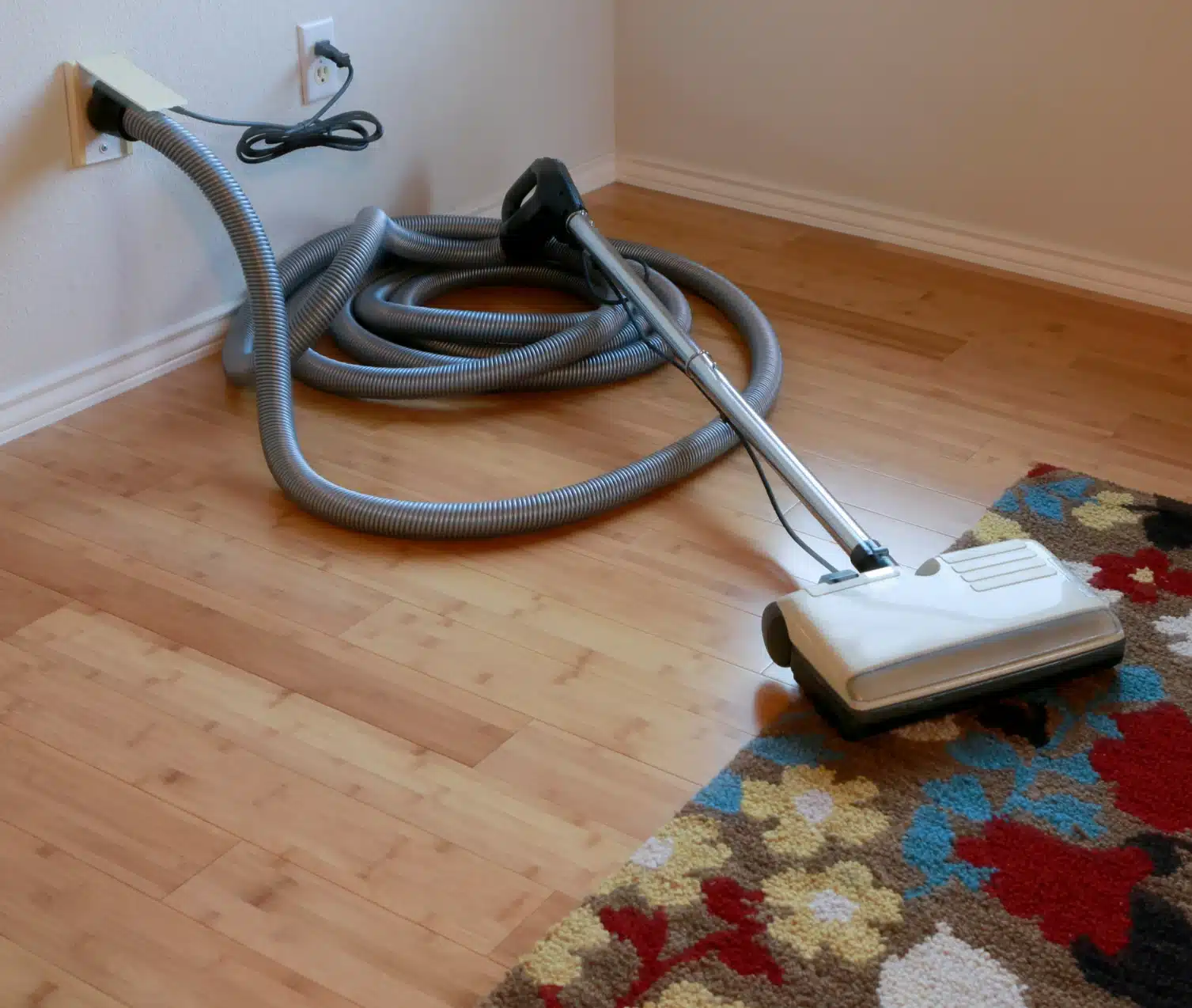 Central vacuum hose and cleaner nozzle on a wooden floor